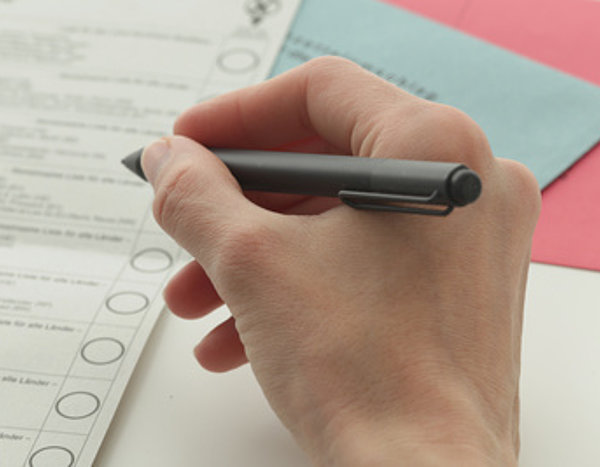 Wahlzettel und Hand mit Stift 