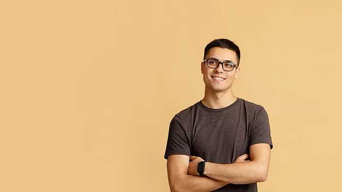 Junger Mann vor einem sandfarbenen Hintergrund