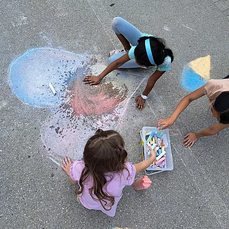 Kinder malen mit Kreide.